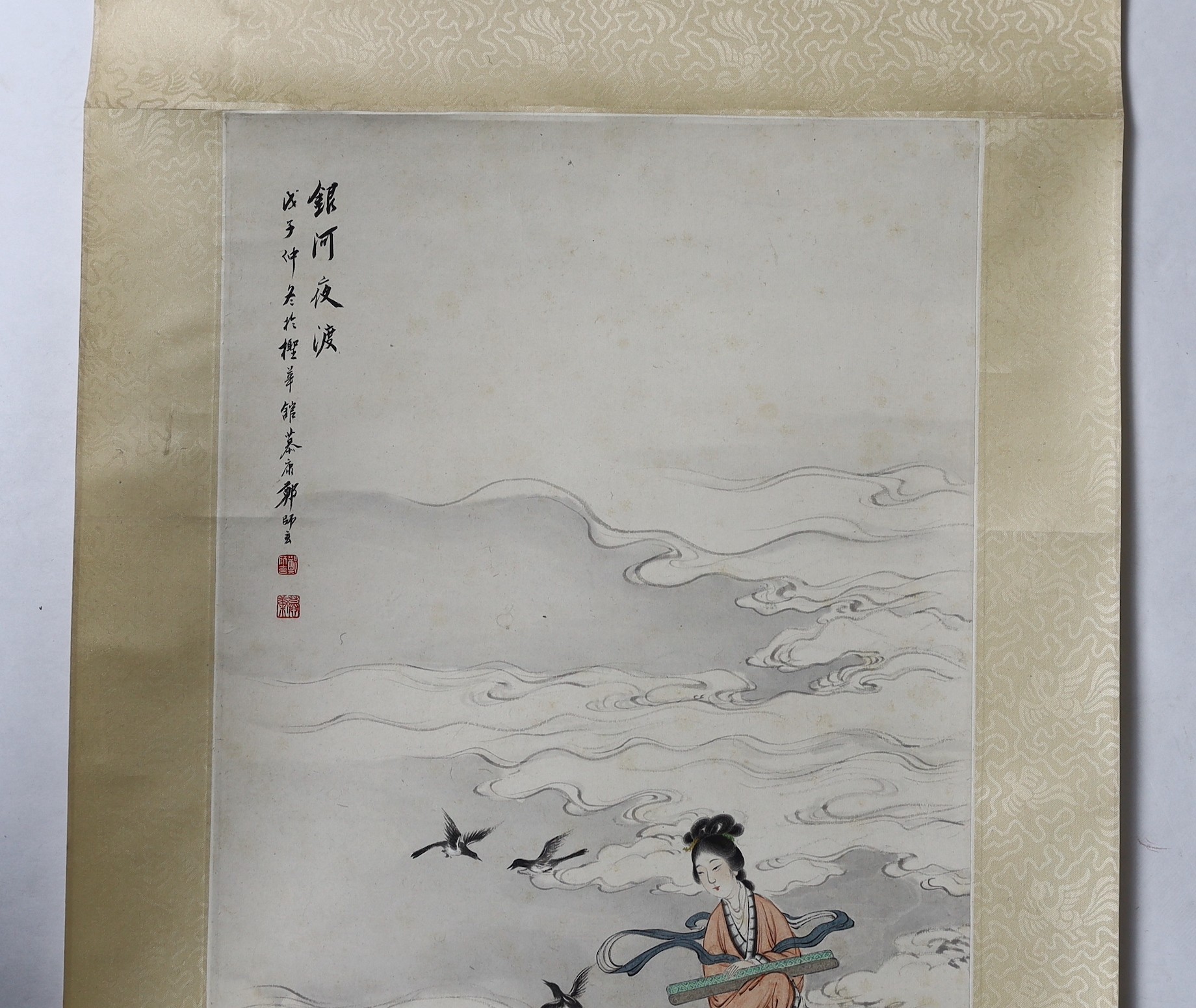 A Chinese scroll painting on paper of a female immortal and a male immortal riding a Buffalo amid clouds and birds, early 20th century, image 77cm x 34.5cm